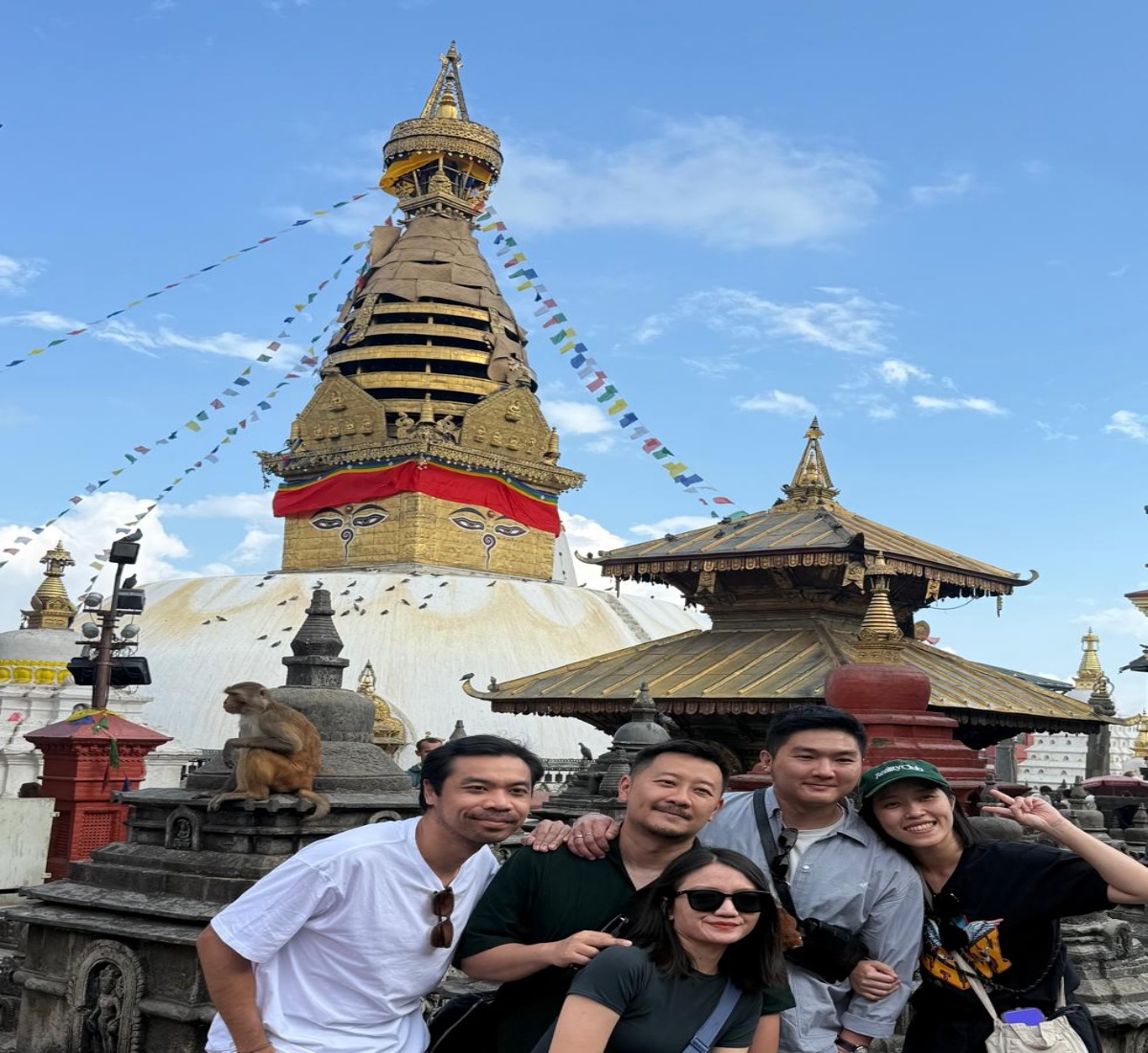 Happy pilgrims posing with a monkey at Swayambhunath Stupa